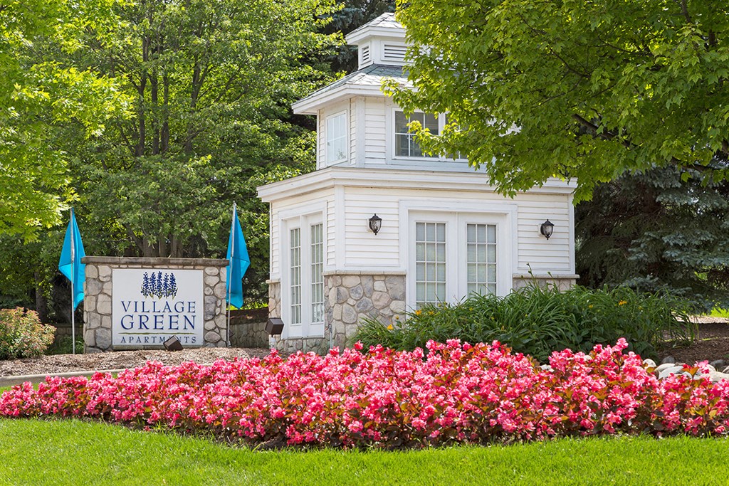 a white building with a sign and pink flowers in front of it