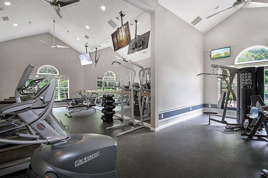 a gym with weights and other exercise equipment in a room with windows