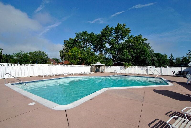 A large outdoor swimming pool surrounded by a white fence.