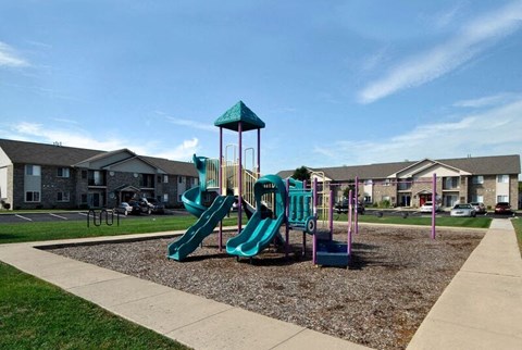 A playground with a green slide and a blue and green play structure.