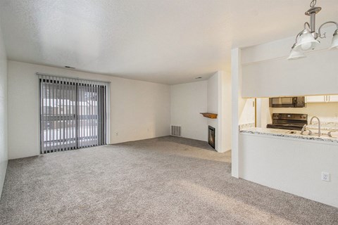 an empty living room with a window and a kitchen