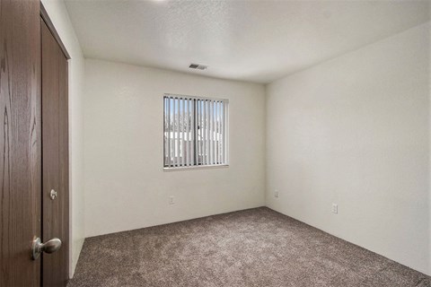 the living room of an empty home with a window and carpet