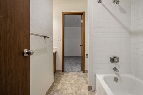 a bathroom with a tub and a shower and a door to a closet