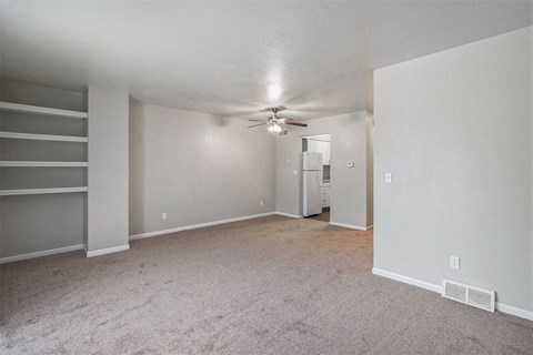an empty living room with carpet and a ceiling fan