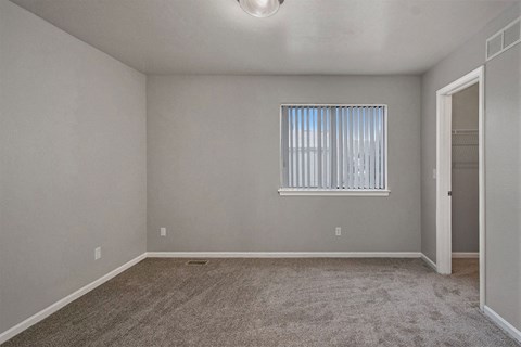 an empty living room with a window and carpet