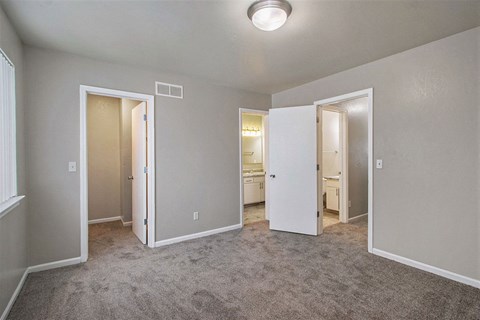 an empty room with a carpeted floor and doors to a bathroom