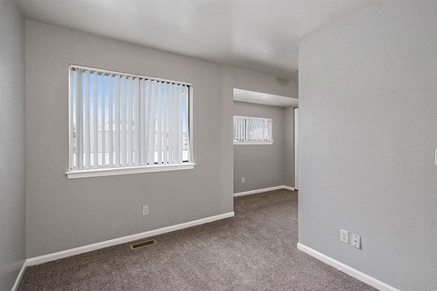 an empty bedroom with a large window and carpeted flooring