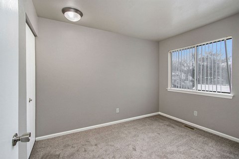 an empty living room with a window and carpet