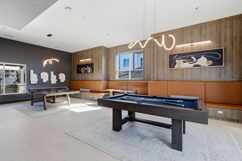 A billiard table is in the middle of a room with a pool table poster on the wall.