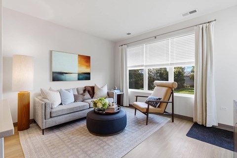 A living room with a grey couch, a round coffee table, and a painting on the wall.