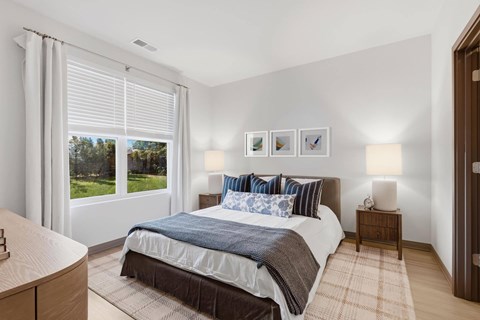 A bedroom with a large bed and a view of trees outside the window.