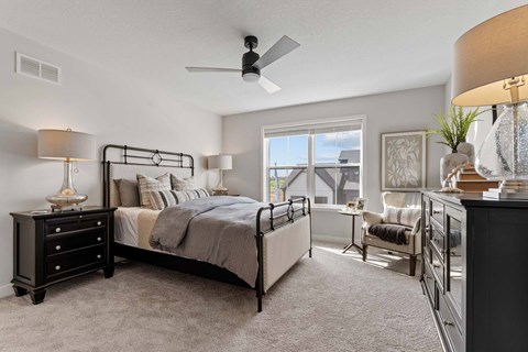 A bedroom with a large bed and a ceiling fan.
