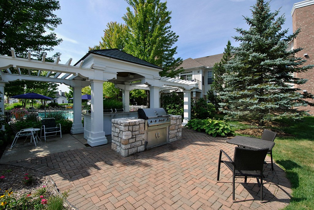 a brick patio with a grill and a pergola