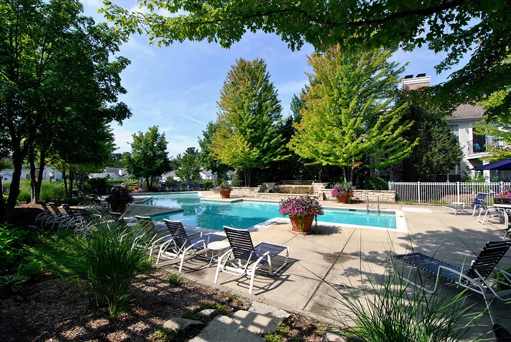 a swimming pool with chairs around it and trees