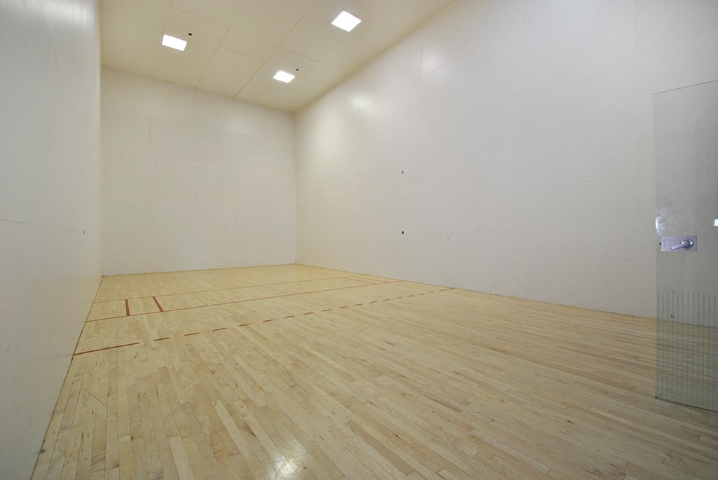 a white room with a wooden floor and a racquetball court