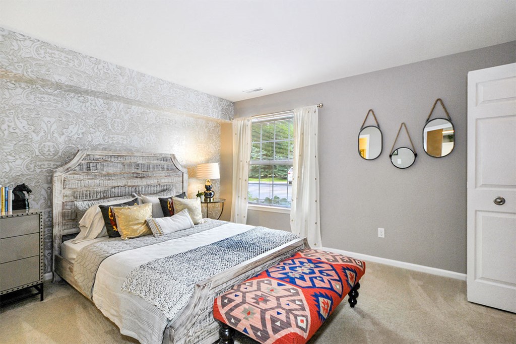 a bedroom with a bed and two mirrors on the wall