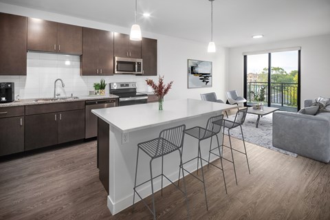 A modern kitchen with a white island and dark brown cabinets.