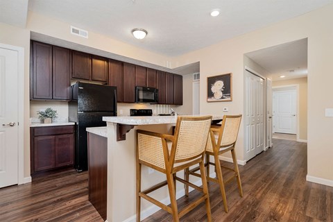 a kitchen with a bar with three chairs