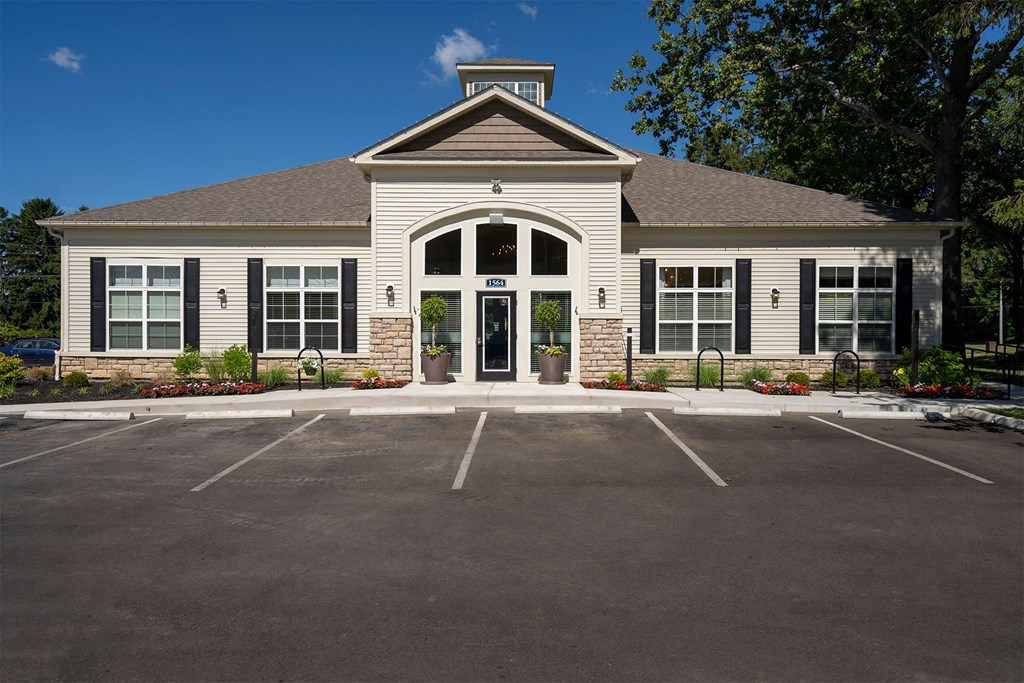 the front of a white house with a parking lot