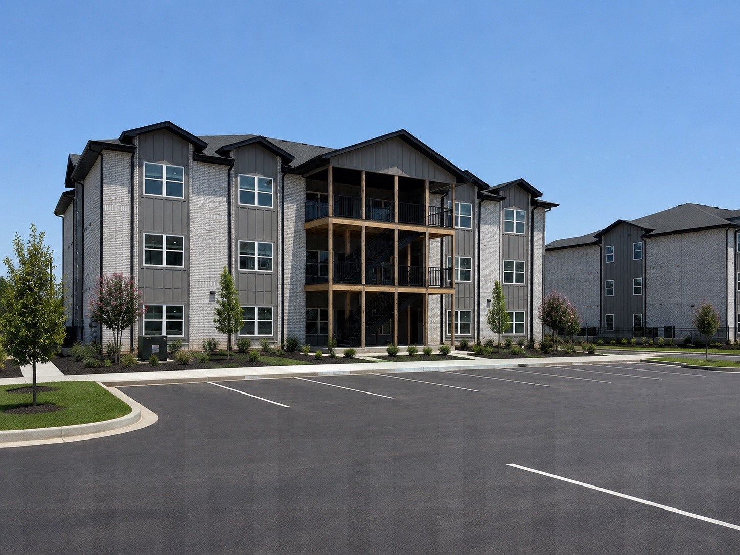 A large, modern apartment complex with a parking lot in front.