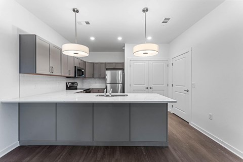 A modern kitchen with a white countertop and grey cabinets.