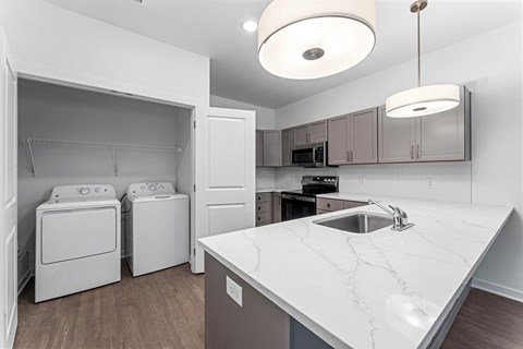 A white kitchen with a marble counter top and a sink.