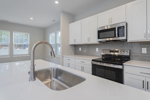 A modern kitchen with a stainless steel sink and stove.
