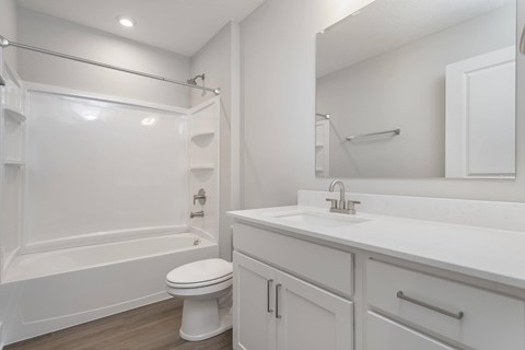 A white bathroom with a toilet, sink, and shower.