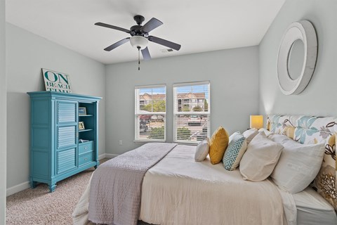 A bedroom with a bed, a dresser, and a window with blinds.