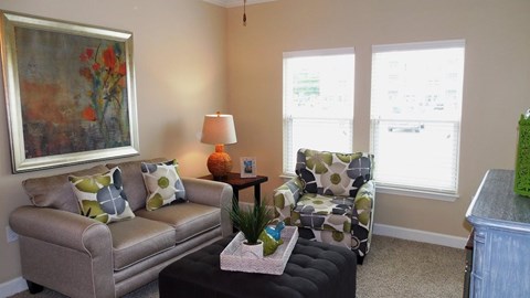 A living room with a couch, chair, and a painting on the wall.