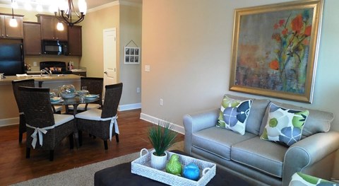 A living room with a grey couch and a painting on the wall.