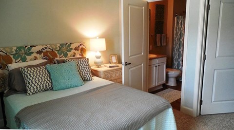 A bedroom with a bed, nightstand, and lamp.