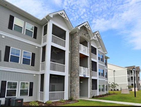 A large two-story apartment building with balconies and a stone pillar.