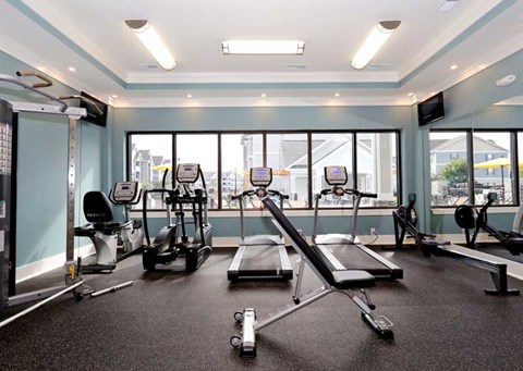 A gym with a variety of equipment including treadmills, weights, and exercise machines.