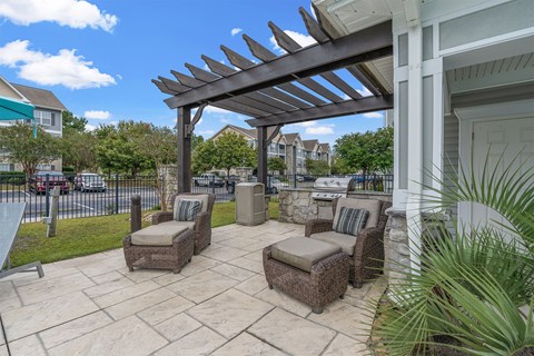 A patio with a white house, a black fence, and a white pergola.