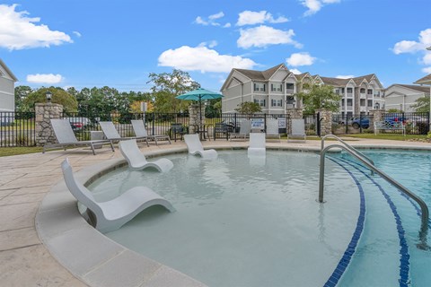 A pool with a slide and sun loungers.