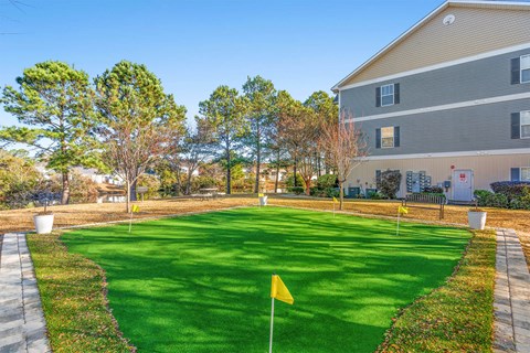 A yellow flag on a green lawn in front of a building.