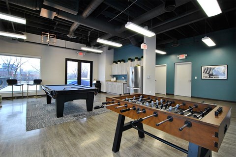 A foosball table is in the middle of a room with a pool table.