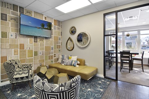A living room with a yellow sofa and a TV mounted on the wall.