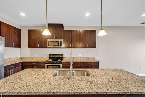 A kitchen with brown cabinets and a granite countertop.