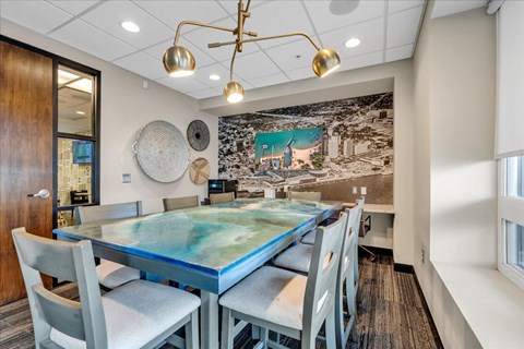 A modern dining room with a glass table and grey chairs.