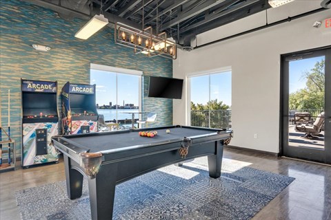 A pool table in a room with a view of the outdoors.