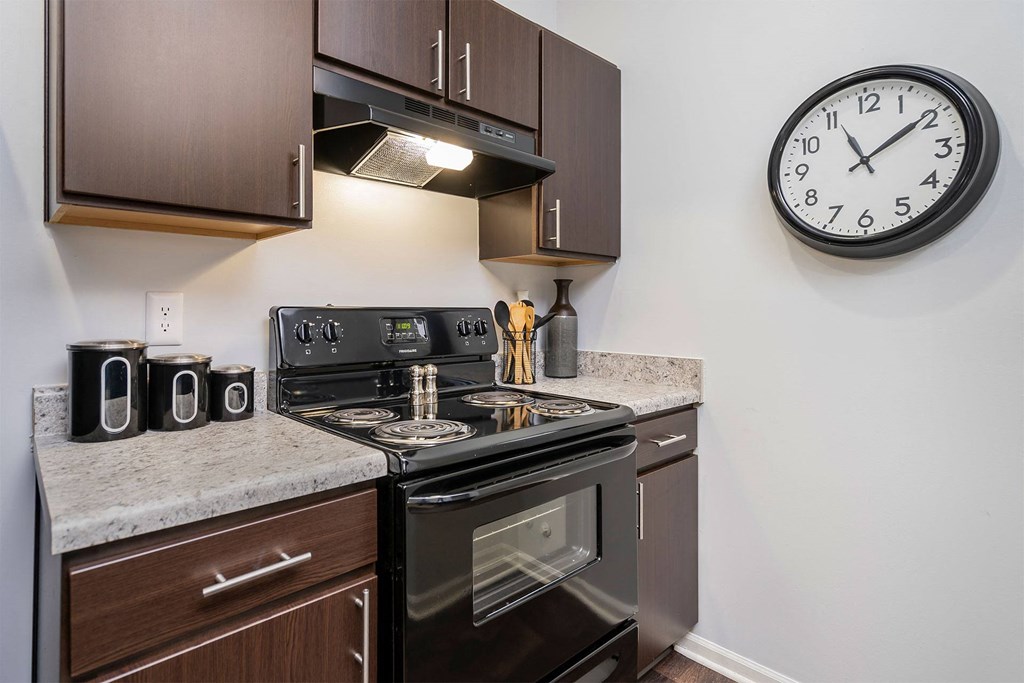 our apartments have a kitchen with a stove and a clock on the wall
