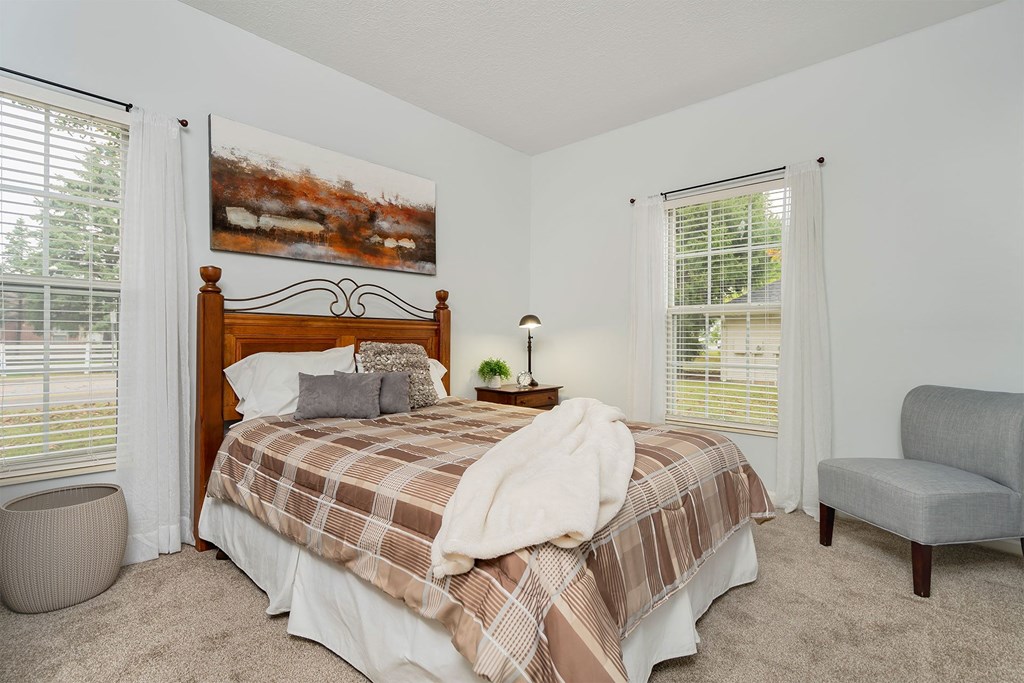 a bedroom with a bed and two windows