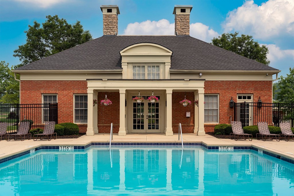 a pool in front of a house with a brick facade