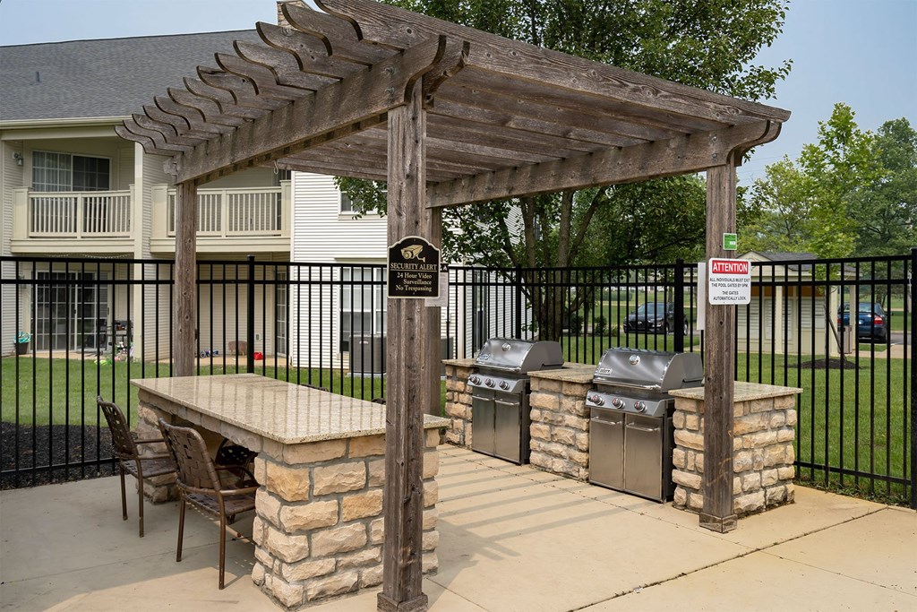 a pergola with a table and chairs and two trashcans in front of a