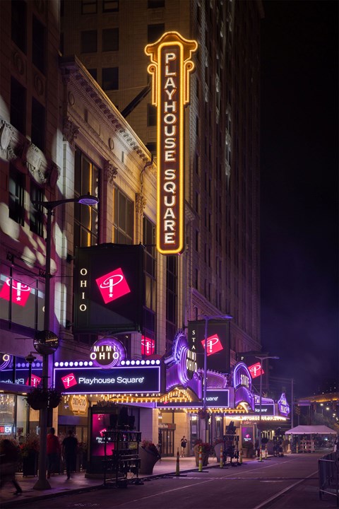 A brightly lit Playhouse Square sign is seen at night.