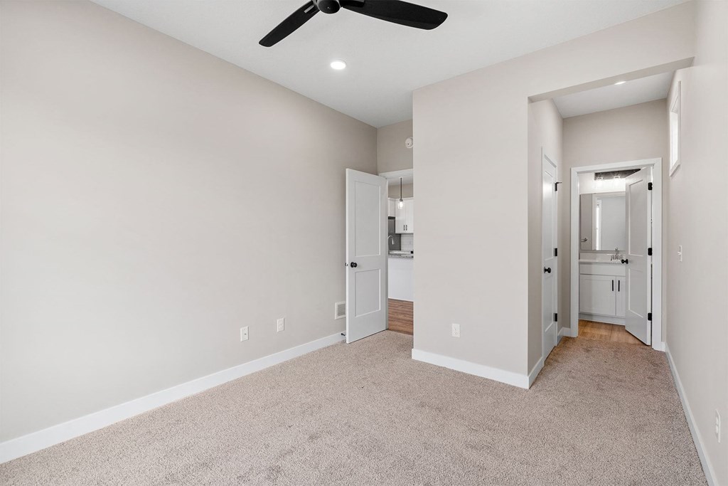 a bedroom with a ceiling fan and carpet