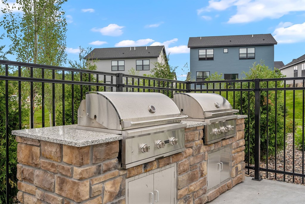 an outdoor kitchen with two bbq grills and a granite countertop