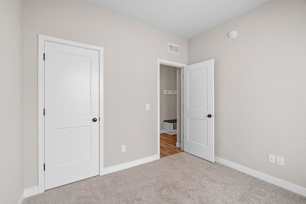 a bedroom with two doors and a carpeted floor